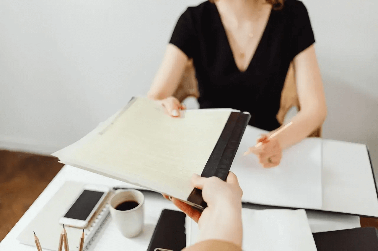 Two people passing between them a note book